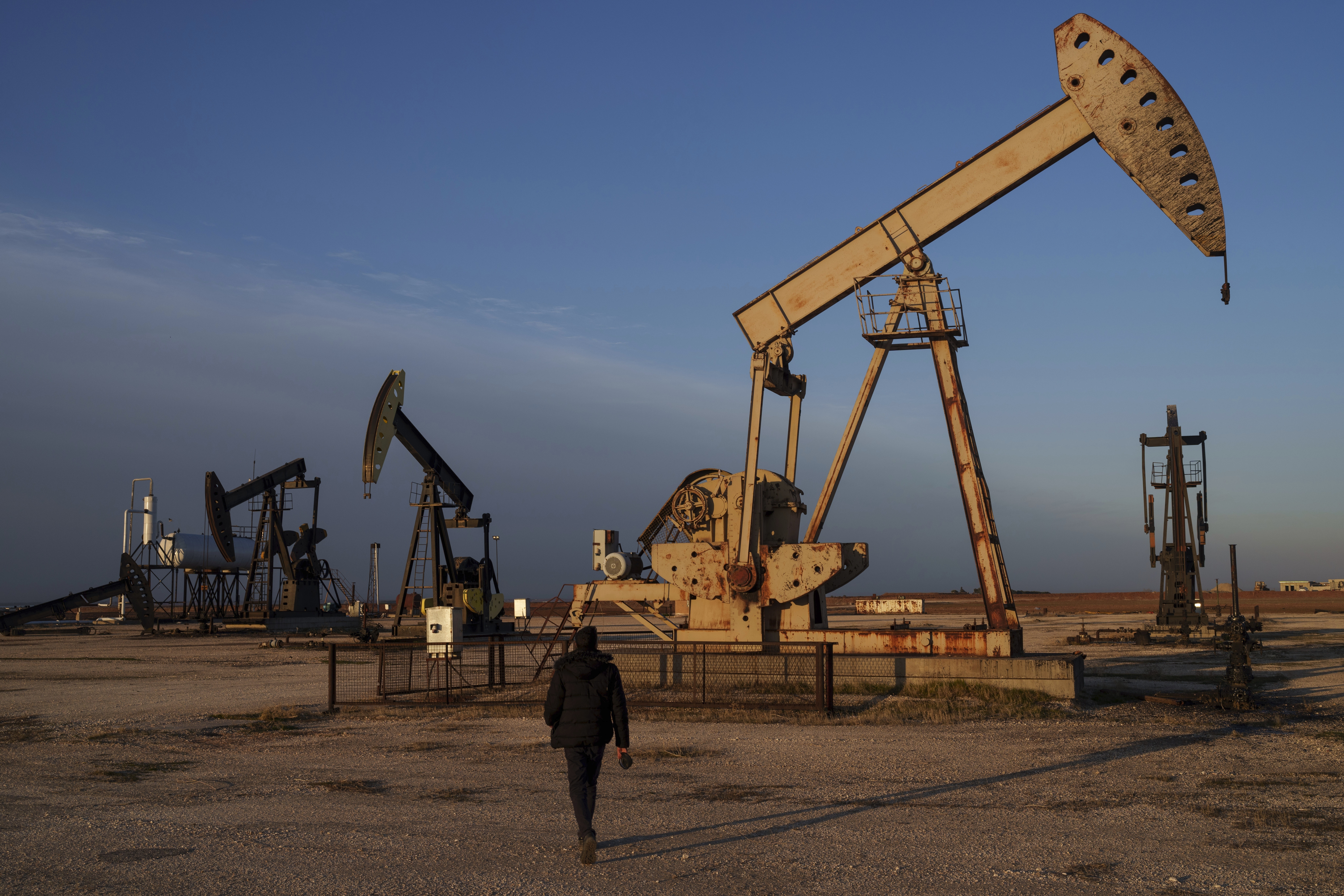 A worker walks past idle pumpjacks at an oilfield on the outskirts of the northeastern Syrian city of Qamishli
