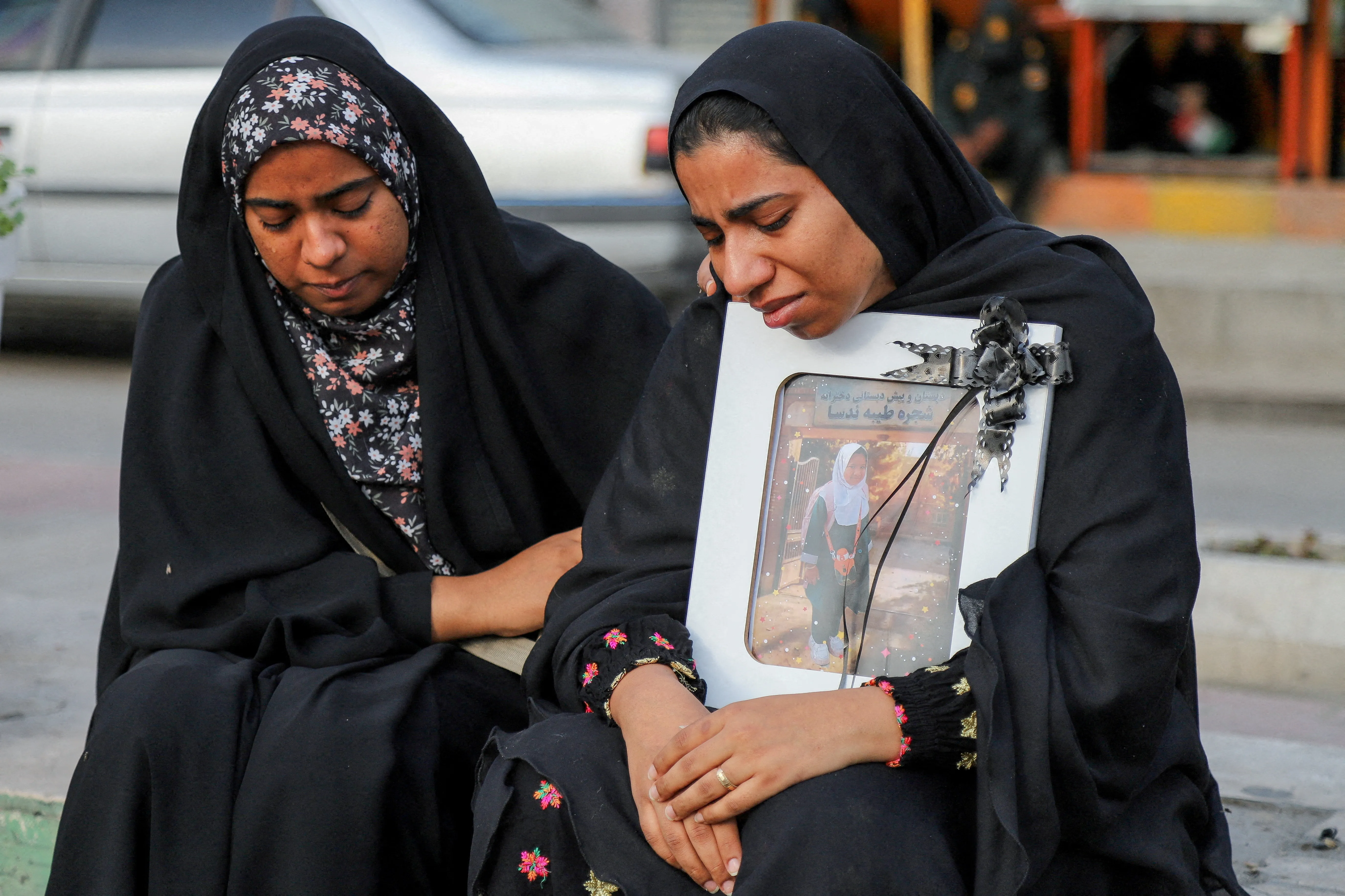 Two women mourn as they hold a photo.